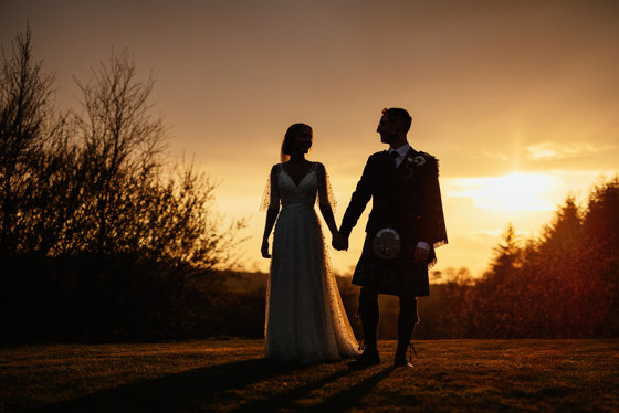 Bride and groom at sunset holding hands